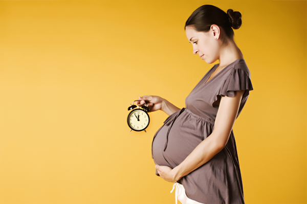 бременна млада жена с часовник